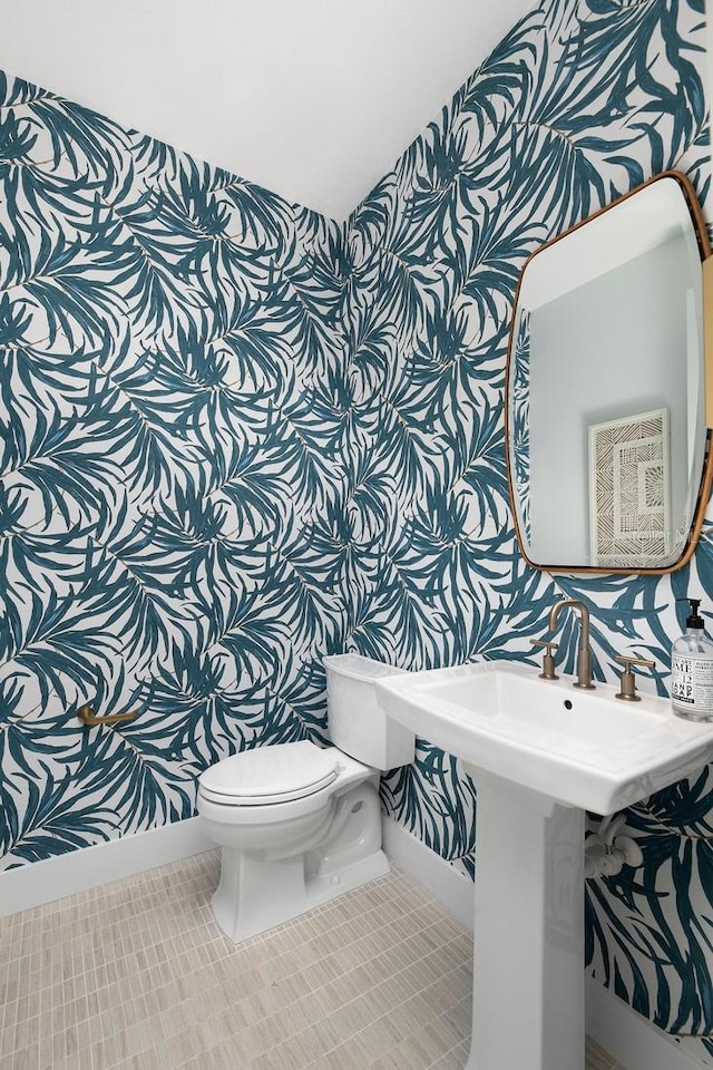 bathroom with tile patterned flooring, toilet, and wallpapered walls