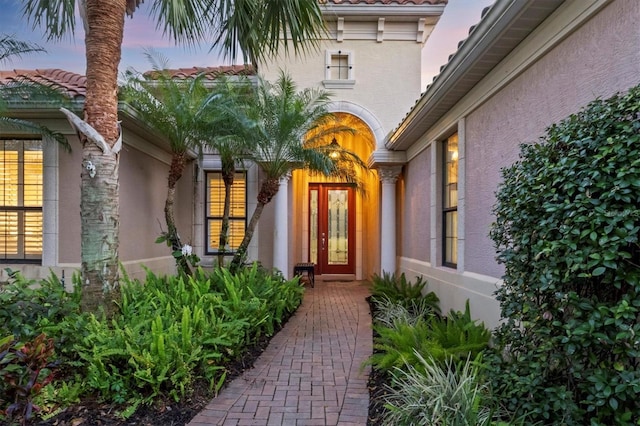 property entrance with a tile roof and stucco siding