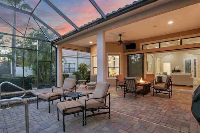 patio terrace at dusk featuring an outdoor fire pit, a lanai, and ceiling fan