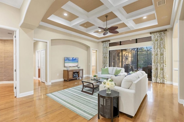 living room featuring light wood-type flooring, a high ceiling, visible vents, and coffered ceiling