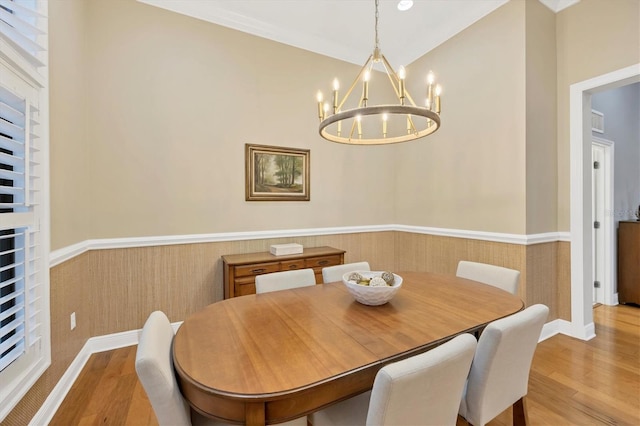 dining room with a wainscoted wall, an inviting chandelier, and wood finished floors