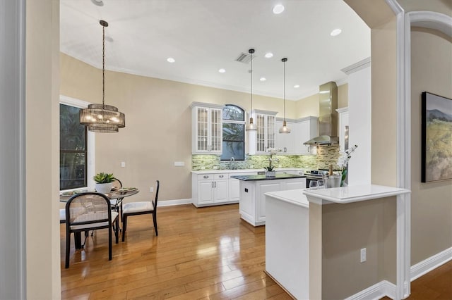 kitchen with electric range, visible vents, glass insert cabinets, a center island, and wall chimney range hood