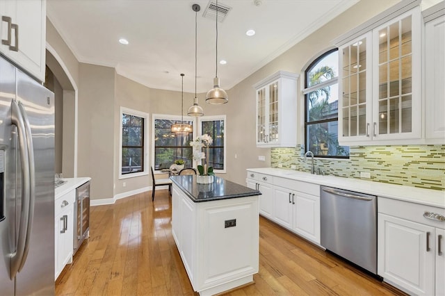 kitchen with a center island, visible vents, backsplash, appliances with stainless steel finishes, and a sink