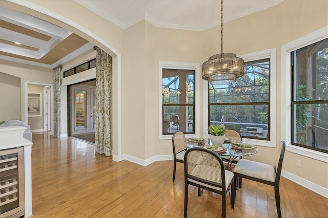 dining area with light wood-style floors, beverage cooler, ornamental molding, and baseboards