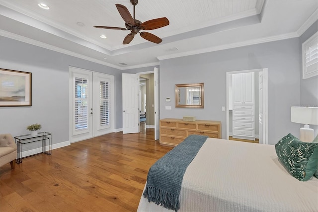 bedroom featuring crown molding, wood finished floors, a raised ceiling, and access to exterior