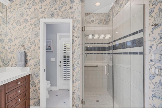 bathroom with tile patterned flooring, toilet, vanity, a shower stall, and wallpapered walls