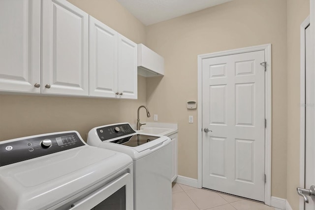 laundry room with light tile patterned floors, cabinet space, a sink, separate washer and dryer, and baseboards