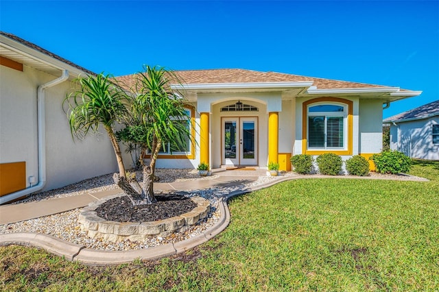 entrance to property with french doors, a lawn, a shingled roof, and stucco siding