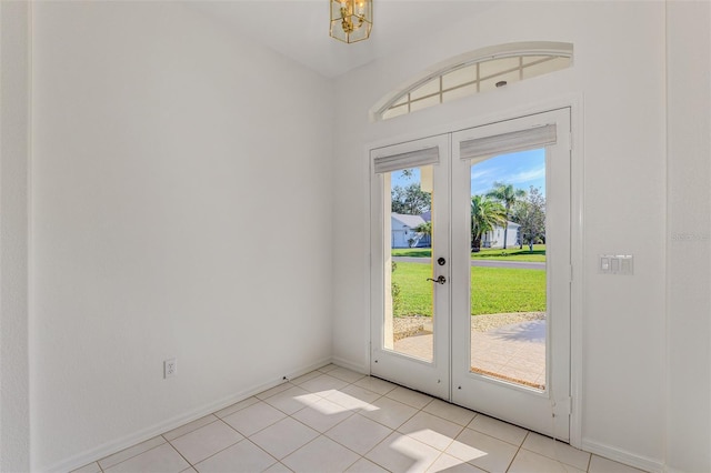 doorway to outside with light tile patterned floors, an inviting chandelier, french doors, and baseboards