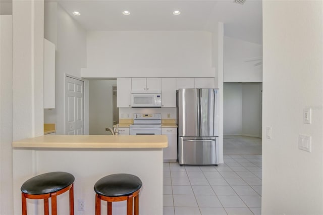 kitchen featuring white cabinets, white appliances, a breakfast bar, and light countertops