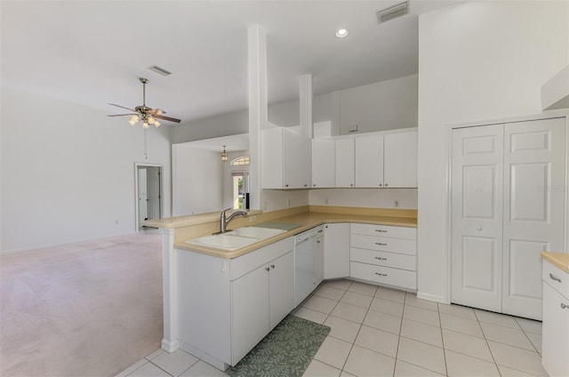 kitchen with visible vents, light countertops, a peninsula, white dishwasher, and a sink