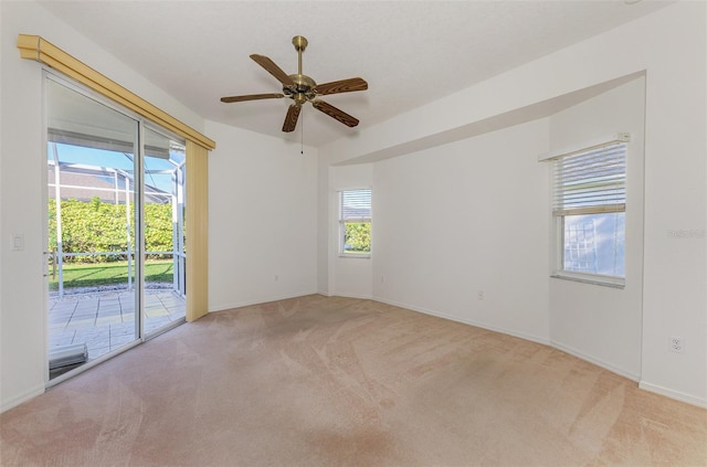 spare room featuring ceiling fan, baseboards, a wealth of natural light, and light carpet