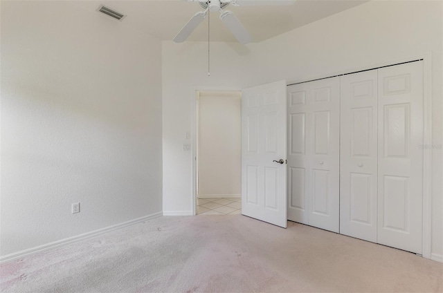 unfurnished bedroom featuring visible vents, baseboards, light colored carpet, a closet, and a ceiling fan