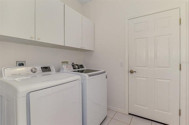 laundry area featuring washing machine and clothes dryer, light tile patterned floors, cabinet space, and baseboards