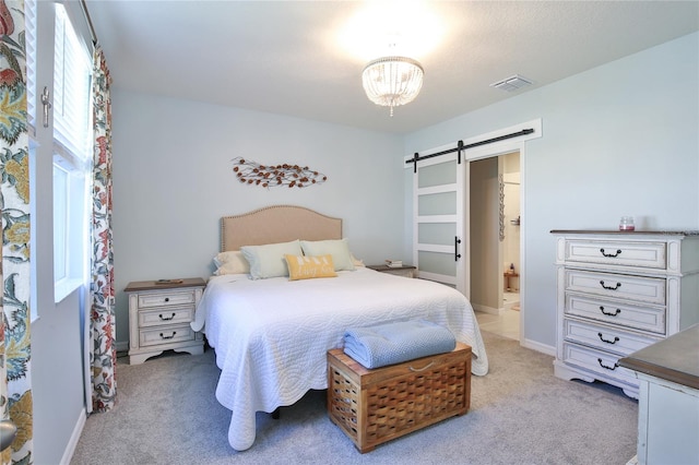 bedroom with light carpet, a barn door, visible vents, baseboards, and connected bathroom