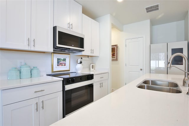 kitchen featuring light countertops, visible vents, white microwave, a sink, and black / electric stove