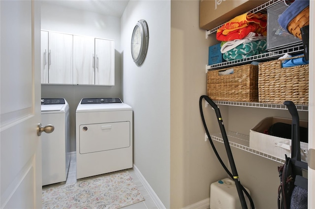 laundry area with separate washer and dryer, tile patterned flooring, cabinet space, and baseboards