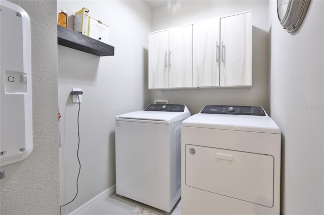 laundry room with cabinet space, baseboards, and separate washer and dryer