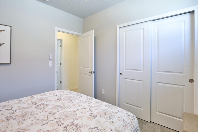 bedroom featuring light carpet, a textured ceiling, and a closet