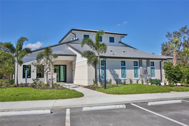 view of front of house with uncovered parking, a front lawn, and stucco siding