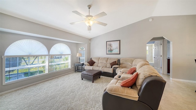 living area featuring arched walkways, ceiling fan, vaulted ceiling, and baseboards