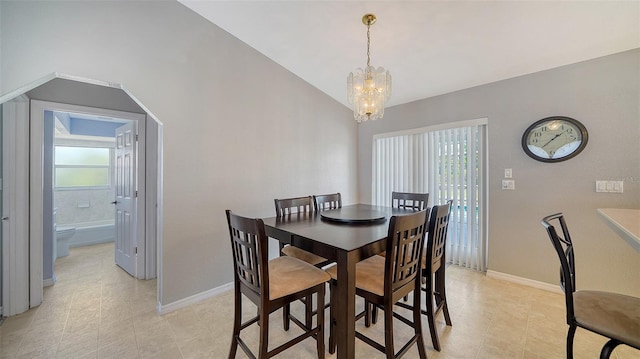 dining area featuring a wealth of natural light, lofted ceiling, baseboards, and an inviting chandelier