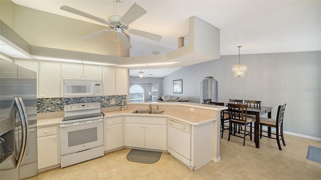 kitchen with white appliances, light countertops, a sink, and a peninsula