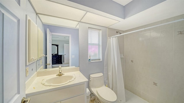 full bath featuring toilet, a tile shower, and vanity