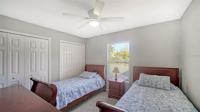 carpeted bedroom with ceiling fan and two closets