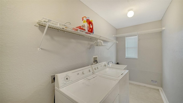 clothes washing area with a sink, laundry area, washing machine and dryer, and baseboards