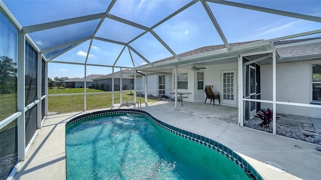 pool with glass enclosure, a patio area, a lawn, and ceiling fan