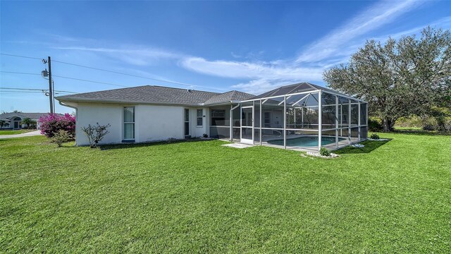 back of house with glass enclosure, a lawn, an outdoor pool, and stucco siding