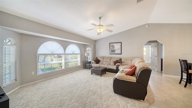 living room with a ceiling fan, arched walkways, vaulted ceiling, and baseboards