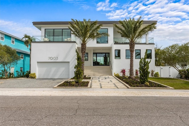 modern home with fence, stucco siding, a balcony, an attached garage, and a gate