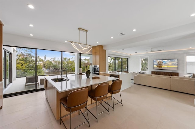 kitchen with an island with sink, light countertops, recessed lighting, modern cabinets, and a sink