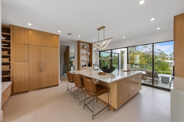 kitchen featuring visible vents, modern cabinets, a center island with sink, open shelves, and a sink