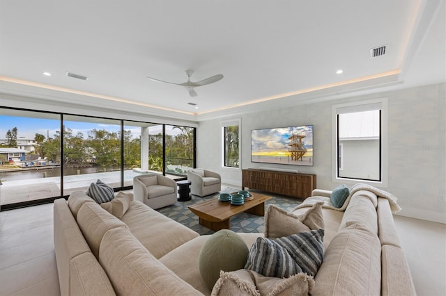 living room featuring visible vents, a healthy amount of sunlight, and a tray ceiling