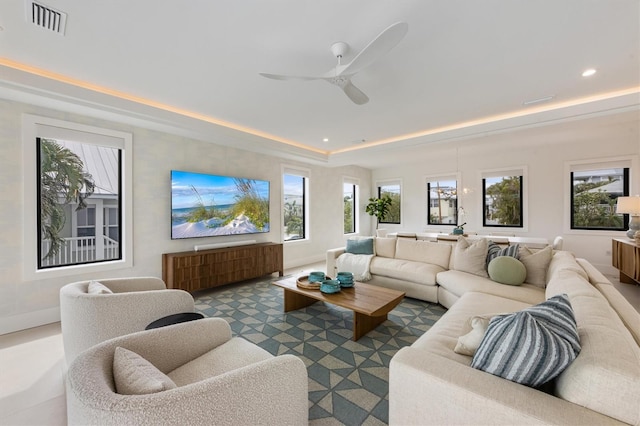 living area with baseboards, visible vents, recessed lighting, ceiling fan, and a raised ceiling