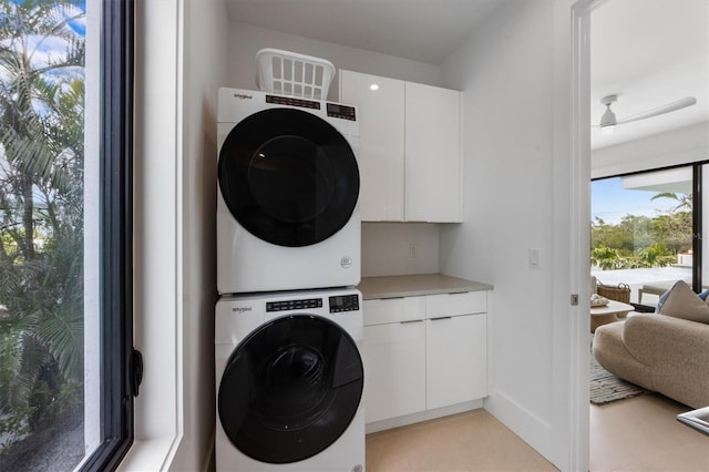 clothes washing area featuring stacked washer / drying machine, cabinet space, and ceiling fan