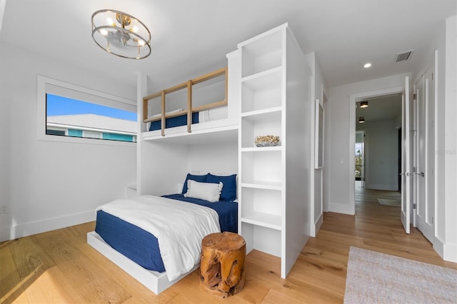 bedroom featuring visible vents, multiple windows, an inviting chandelier, and wood finished floors