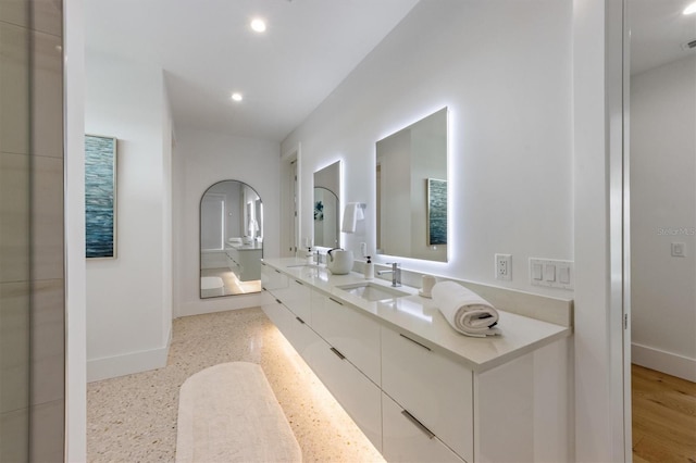 bathroom with a sink, baseboards, double vanity, and recessed lighting