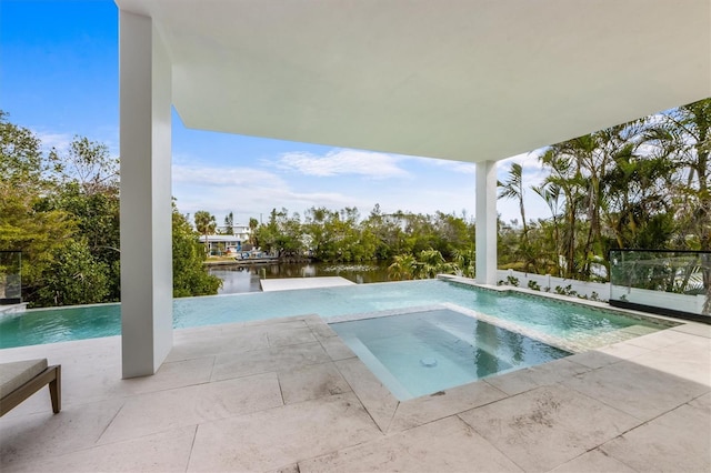 pool with a water view, an in ground hot tub, and a patio area