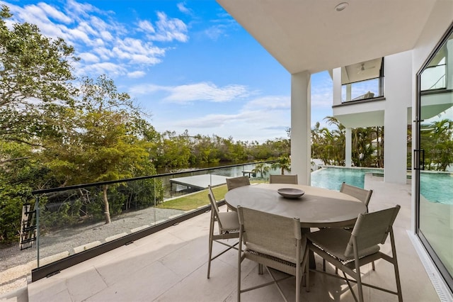 balcony featuring a patio area, outdoor dining area, and a water view