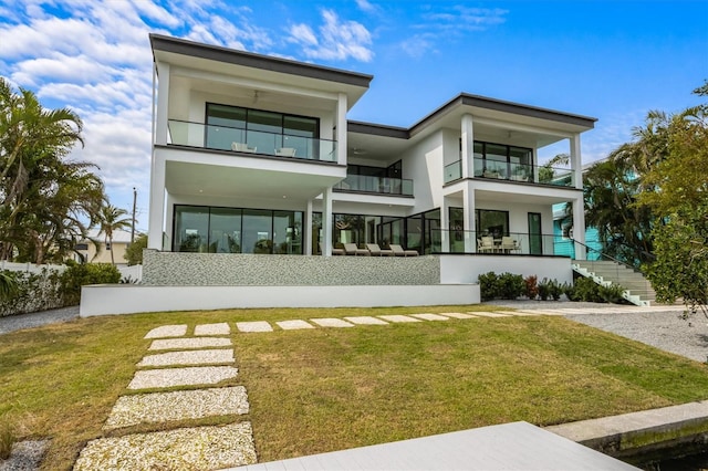 back of property with stairway, a balcony, and a yard