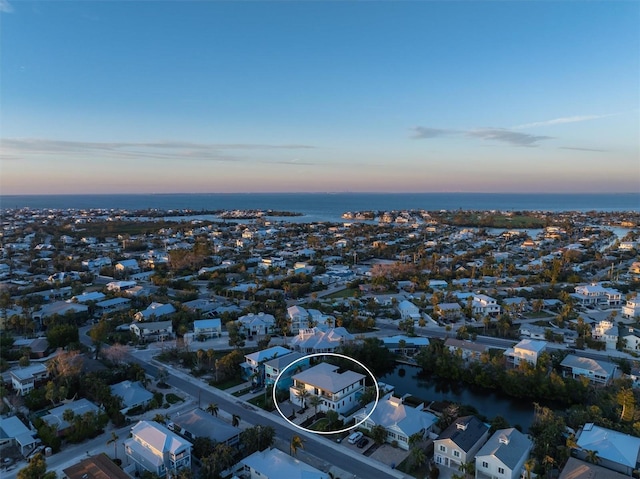 aerial view at dusk with a water view and a residential view