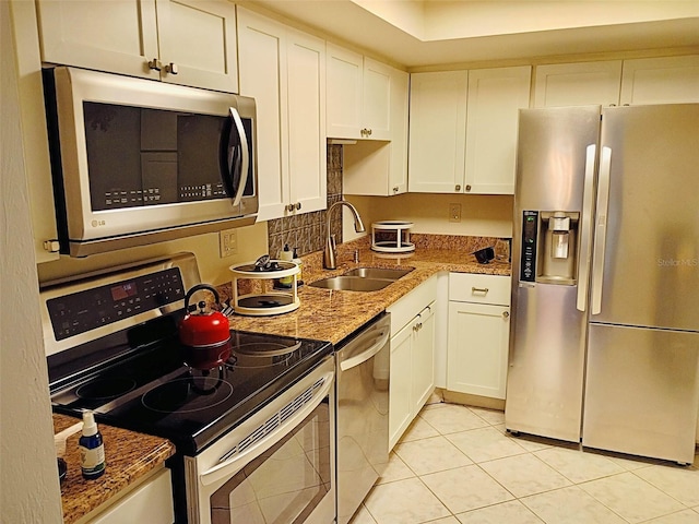 kitchen with white cabinets, light stone counters, stainless steel appliances, and a sink