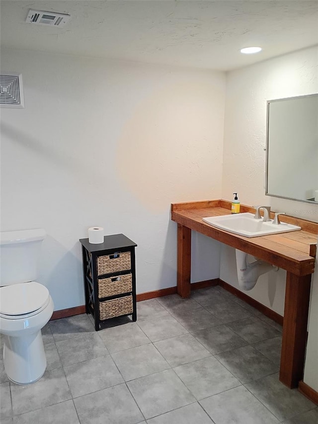 half bath with baseboards, visible vents, toilet, and tile patterned floors