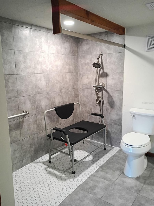 bathroom featuring toilet, tiled shower, beam ceiling, and visible vents