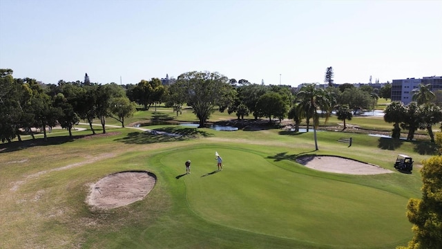 view of property's community featuring view of golf course and a lawn