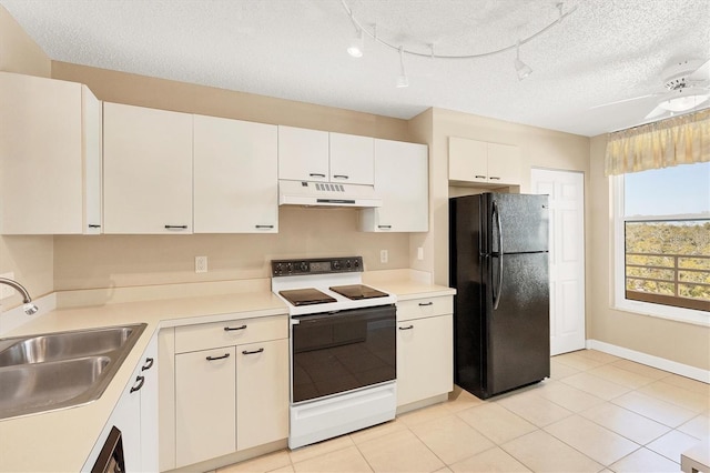 kitchen with under cabinet range hood, a sink, electric stove, light countertops, and freestanding refrigerator